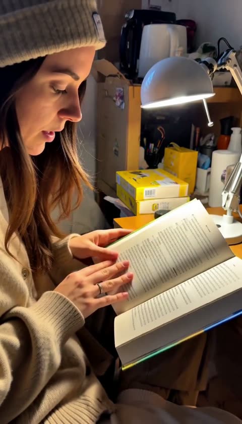AI-generated presenter showing an open book beside a desk lamp
